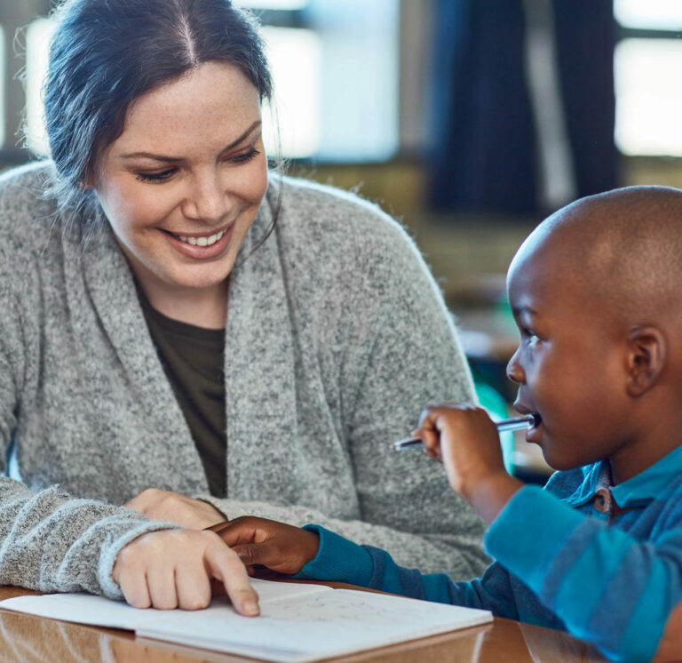 A literacy teacher points to a word in a workbook as her student sounds it out.