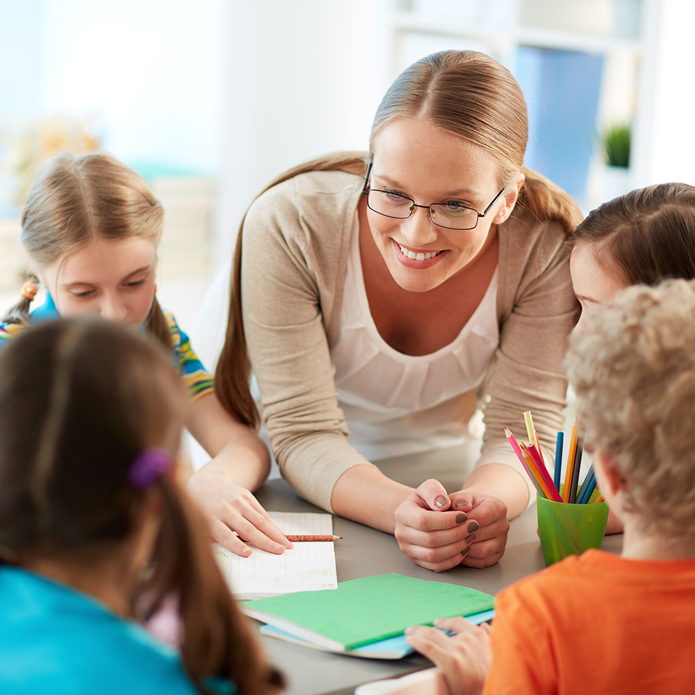 A teacher listening to her students as they work through phonics lessons