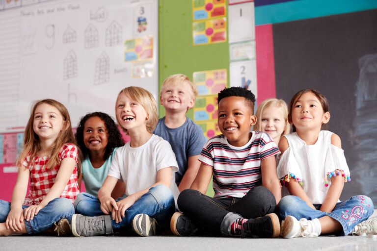 Group Of Elementary School students Sitting On Floor In Classroom