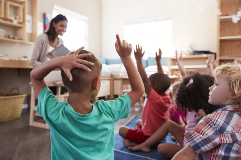 elementary students raising their hands during reading instruction