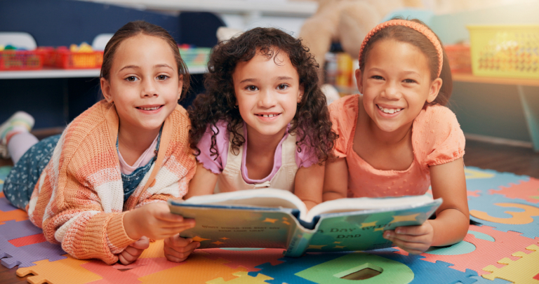 School kids, group and portrait on floor with reading book, learning and smile together with diversity for education